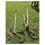 Two vintage metal and wood plows with spoked wheels 