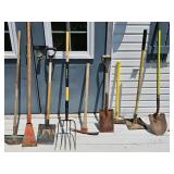 Group of assorted garden tools including shovels, rakes, and hoes