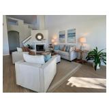 Living room with two club chairs, sofa, side tables, rug, wall art and faux plants