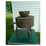 Picture of stove on legs and copper pot resting on grate on top of stove