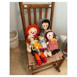 Antique rocker with rush seat with a collection of Rag Dolls