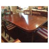 Dining table with two leaves and pads, and six carved, upholstered chairs.