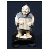 Netsuke Man Holding Ribbed Board On Wood Base