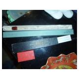 misc collection of vintage items, cardboard serving plate, hair nets, toothpick angels for cake decorating I assume, old sunbeam iron box, slide rule, baby shoes, and a mustimeter
