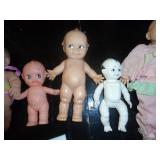 group of vintage dolls, far left is a berenger, 3 kewpies, one is ceramic/porcelain connected with string, all moveable joints