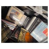 A 20"W Tote full of over 200 combined of DVDs, CDs, and Cassettes