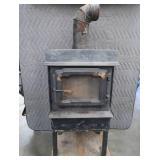 BLACK CAST IRON STOVE ON STAND WITH ROOF VENT