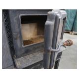 BLACK CAST IRON STOVE ON STAND WITH ROOF VENT