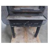BLACK CAST IRON STOVE ON STAND WITH ROOF VENT