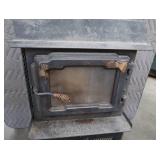 BLACK CAST IRON STOVE ON STAND WITH ROOF VENT
