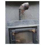 BLACK CAST IRON STOVE ON STAND WITH ROOF VENT