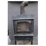 BLACK CAST IRON STOVE ON STAND WITH ROOF VENT