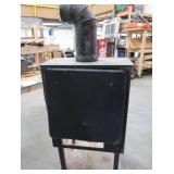 BLACK CAST IRON STOVE ON STAND WITH ROOF VENT