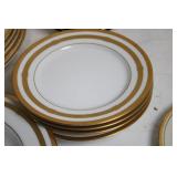 Set of Elegant Porcelain Dinnerware with Gold Trim and Decorative Plate