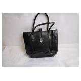 Black Leather Handbag with Intricate Silver Accent & Vintage Wooden Cabinet
