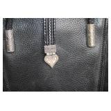 Black Leather Handbag with Intricate Silver Accent & Vintage Wooden Cabinet