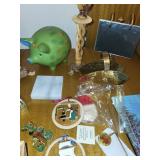 Assorted Home Decor Items Including Coasters, Candle, Piggy Bank, and Handbell