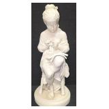 Sculpture of a woman sitting on a stool and reading a book