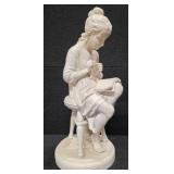 Sculpture of a woman sitting on a stool and reading a book