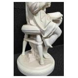 Sculpture of a woman sitting on a stool and reading a book