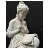 Sculpture of a woman sitting on a stool and reading a book