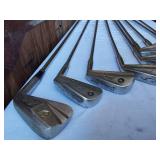 Golf equipment set including Johnny Miller Signature irons, wooden drivers, and a bag with assorted golf balls