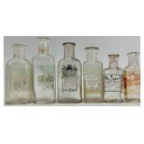 Collection of 12 Antique Glass Water Slide Bottles with Original Labels