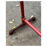 Red Metal Pipe Frame Clothing Stand and Roll of Perforated Metal