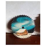 A signed hand-painted saw blade by M. Cadlen 2002 and a hand-painted scenery wood cut out saw blade clock