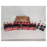 Collection of Vintage Coca-Cola Bottles with Holiday Labels and Wooden Crate