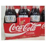 Collection of Vintage Coca-Cola Bottles with Holiday Labels and Wooden Crate