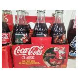 Collection of Vintage Coca-Cola Bottles with Holiday Labels and Wooden Crate