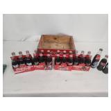 Collection of Vintage Coca-Cola Bottles with Holiday Labels and Wooden Crate