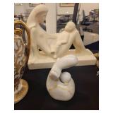 A table full of decor items, animal figures, pottery, glassware, bookends, candle holders, dolls etc.