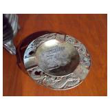 two decorative items: a miniature potbelly stove and a round ashtray.