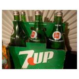 several bottles of 7UP soda in a vintage-style green cardboard carrier.