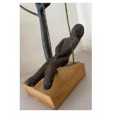 LL  - Metal Sculpture of Child on Swing Under Tree