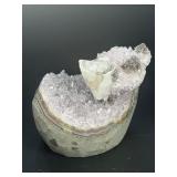 A stunning Amethyst crystal perched on its natural matrix, featuring delicate Calcite inclusions that add depth and character.