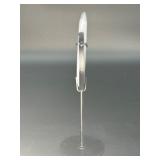 A luminous Botswana Agate druzy carved into a moon shape, showcasing delicate bands of soft gray, caramel, and cream. The sparkling druzy surface catches the light, in a custom metal stand.