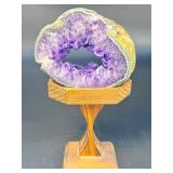 A mesmerizing deep amethyst portal, showcasing rich violet crystals that form a natural, glowing window into the stone’s heart. On a custom wooden stand.