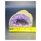 A mesmerizing deep amethyst portal, showcasing rich violet crystals that form a natural, glowing window into the stone’s heart. On a custom wooden stand.