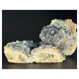 A striking specimen of large blue fluorite perched atop a clear quartz crystal matrix.