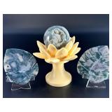 A serene moss agate collection featuring two hand-carved leaf-shaped pieces and a polished sphere with a druzy center resting on a lotus stand.