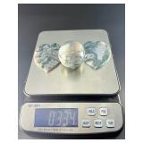 A serene moss agate collection featuring two hand-carved leaf-shaped pieces and a polished sphere with a druzy center resting on a lotus stand.