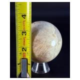 Moonstone Sphere with Blue Flashes is a captivating crystal sphere known for its soft, luminous glow and stunning blue flashes that shimmer as the light moves across its surface.