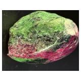 Ruby Zoisite is a striking natural stone that beautifully blends vibrant ruby inclusions with earthy green zoisite, often accented by dark hornblende veins.