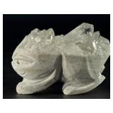 Hand-Carved Quartz Frog Cluster is a charming and energetically vibrant crystal piece, expertly carved into the shape of a frog while preserving the natural beauty of the quartz cluster.