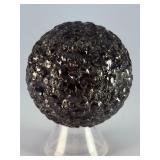 Chiseled Obsidian Sphere is a bold and captivating crystal sphere sculpted from natural obsidian. Its smooth, polished surface is enhanced with subtle chiseled facets, creating depth, texture, and a d