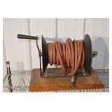 Hose Reel with Red Rubber Hose on a Metal Spool and Hand Crank