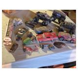 Assorted Toy Vehicles and Accessories Lot including Monster Trucks, Cars, and Tank